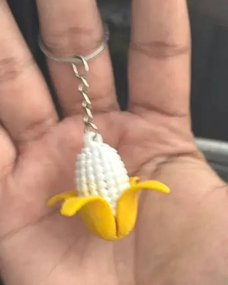 Llavero de elote con granos blancos y hojas amarillas abiertas.