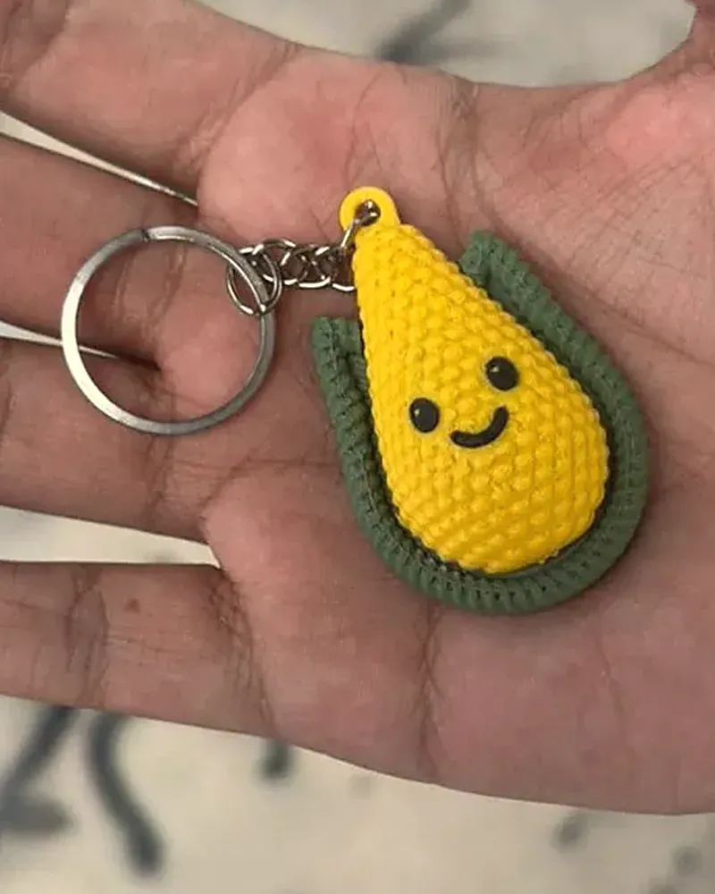 Llavero de elote amarillo con carita sonriente y hojas verdes.